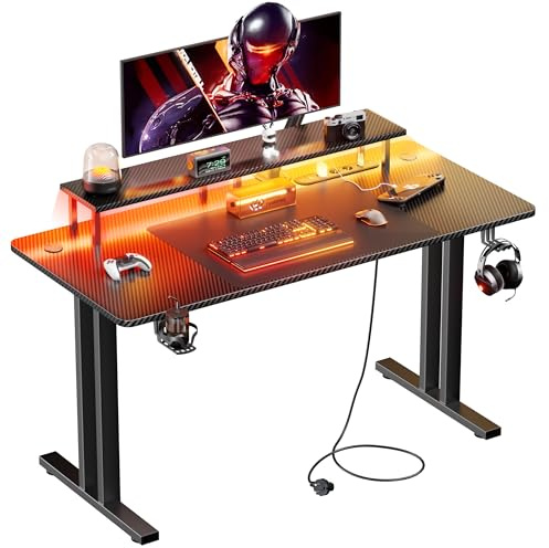 HLFURNIEU Mesa Gaming LED 120 x 60 cm, Escritorio Gaming con Enchufes & Puertos USB, Mesa Gamer con Soporte para Monitor, Portavasos y Gancho para Auriculares, Superficie de Fibra de Carbono, Negro